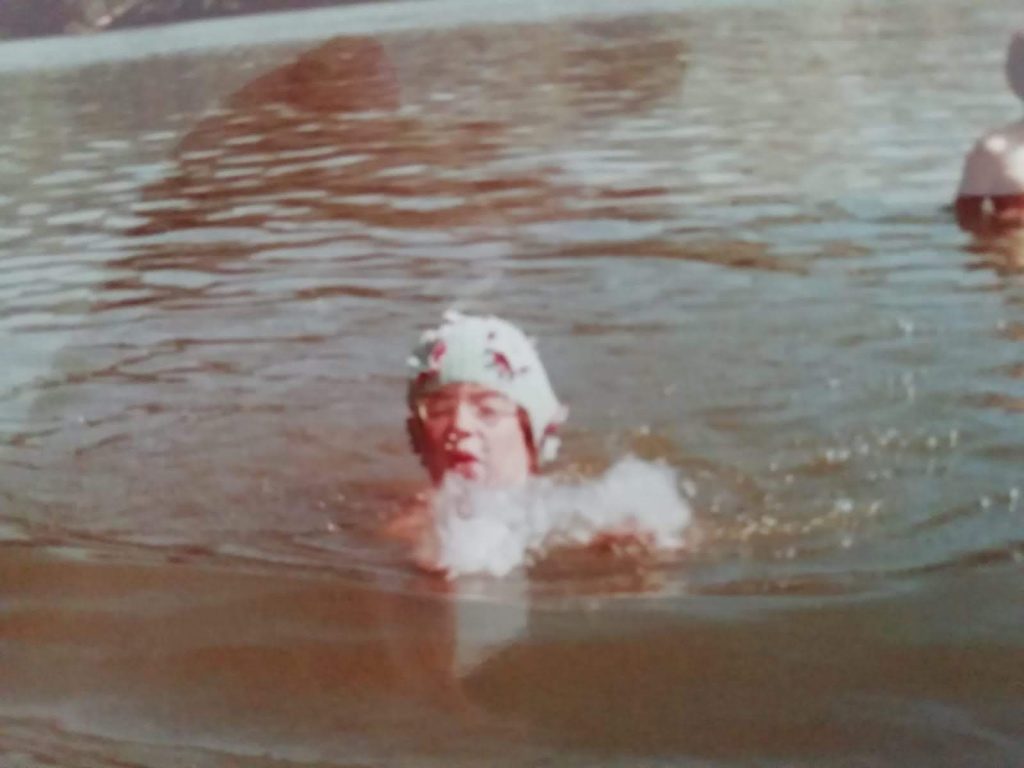 Anne im Badesee als Kind, Kopf über Wasser, Brille auf.